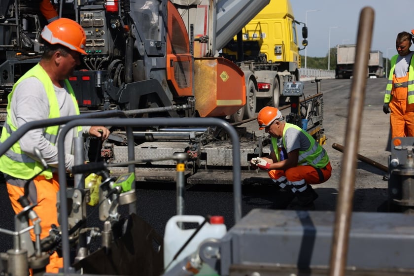 Robotnicy pracujący na wiadukcie, układają ostatnią warstwę nawierzchni