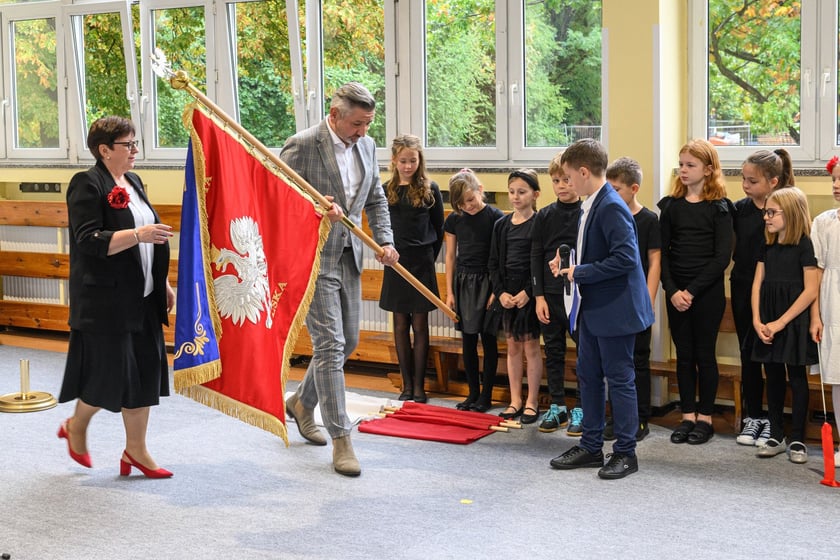 Uroczystości nadania imienia Szkole Podstawowej nr 4 we Wrocławiu &ndash; Jarosław Delewski, dyrektor Departamentu Edukacji przekazuje sztandar dyrektorce&nbsp;Teresie Bartnickiej-Romanowskiej&nbsp;