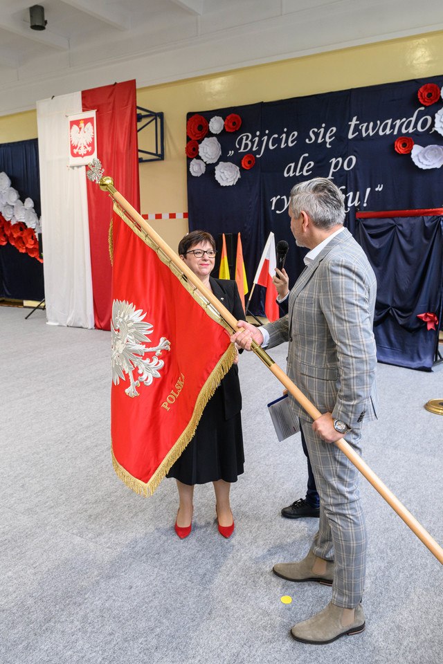 Uroczystości nadania imienia Szkole Podstawowej nr 4 we Wrocławiu &ndash; Jarosław Delewski, dyrektor Departamentu Edukacji przekazuje sztandar dyrektorce&nbsp;Teresie Bartnickiej-Romanowskiej&nbsp;