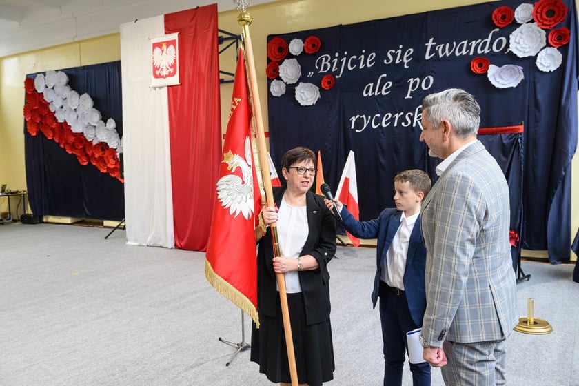 Uroczystości nadania imienia Szkole Podstawowej nr 4 we Wrocławiu &ndash; Jarosław Delewski, dyrektor Departamentu Edukacji przekazuje sztandar dyrektorce&nbsp;Teresie Bartnickiej-Romanowskiej&nbsp;