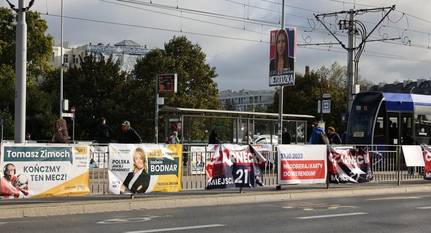 Plakaty wyborcze na ogrodzeniu przystanku