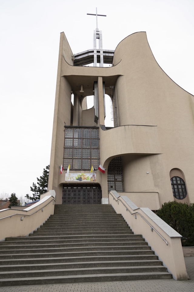 Kości&oacute;ł pw. Tr&oacute;jcy Świętej powstał na przebudowie budynku mieszkalnego. Starania o wzniesienie świątyni trwały kilkanaście lat. Projekt zrealizowano w latach 1979-1987. Bryła budowli jest zwarta, o zaokrąglonych narożach i tr&oacute;jkątnych aneksach. Dwie ściany zasłaniające dach wznoszą się łukami ku g&oacute;rze, tworząc w miejscu styku wieżę z przeszkleniem, spiętą konstrukcją żelbetową. W dolnej partii elewacji są arkadowe wnęki. W budowli mieści się kości&oacute;ł g&oacute;rny i dolny, zakrystia, pomieszczenia pomocnicze i księgarnia.