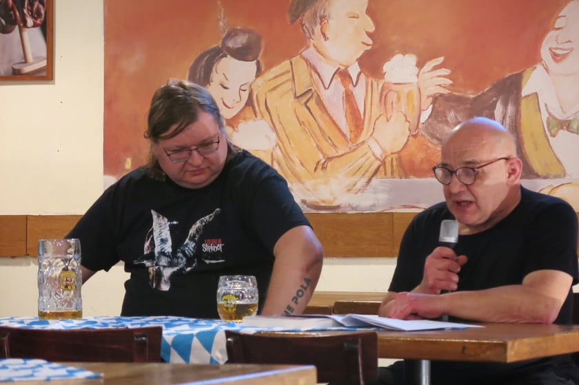 Przemysław Wojcieszek podczas spotkania autorskiego, obok Jacek Zawadzki czyta fragmenty powieści &bdquo;Świnie wojny&rdquo;