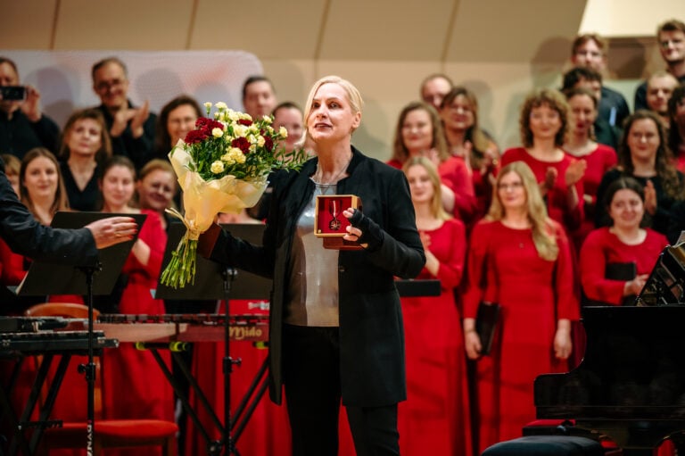 Powiększ obraz: Wręczenie Medalu Gloria Artis podczas Festiwalu Barbórkowego Chórów Akademickich. Na pierwszym planie kierowniczka artystyczna - Małgorzata Sapiecha-Muzioł z medalem, w tle chór.