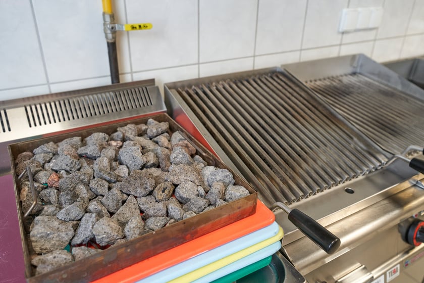Po lewej grill lawowy: zasilany gazem z kamieniami lawowymi, kt&oacute;re choć długo się nagrzewają, to długo też trzymają ciepło. W grillu jest też ruszt ryflowany, kt&oacute;ry zapobiega skapywaniu tłuszczu na kamienie, dzięki czemu dania są zdrowsze.
Po prawej grill wodny: zasilany elektrycznie, z aromatyzerem; to grill gł&oacute;wnie do przygotowywania mięsa, kt&oacute;re podczas normalnego grillowania mocno się wysusza.