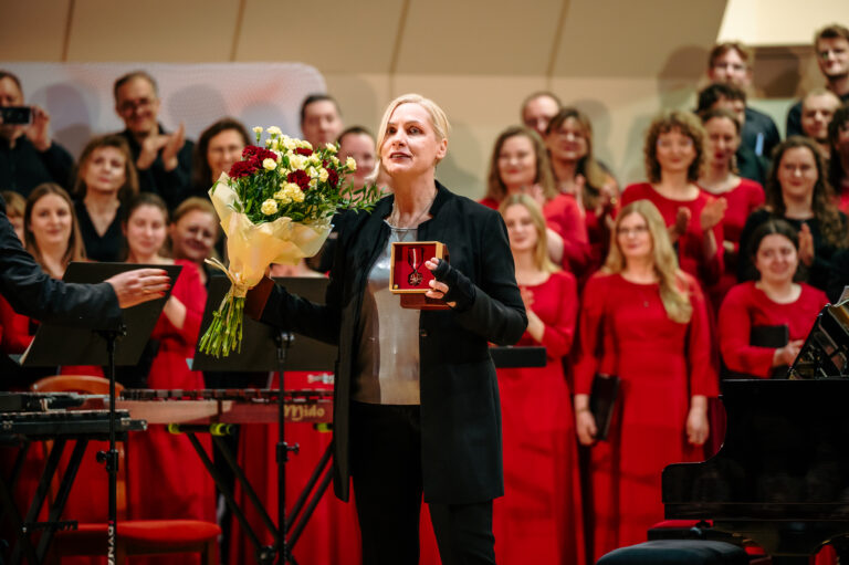 Wręczenie Medalu Gloria Artis podczas Festiwalu Barbórkowego Chórów Akademickich. Na pierwszym planie kierowniczka artystyczna - Małgorzata Sapiecha-Muzioł z medalem, w tle chór.