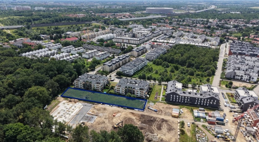 Zdjęcie lotnicze z zaznaczonym obszarem na którym powstanie plac zabaw i strefa sportowa przy Alei Śliwowej.