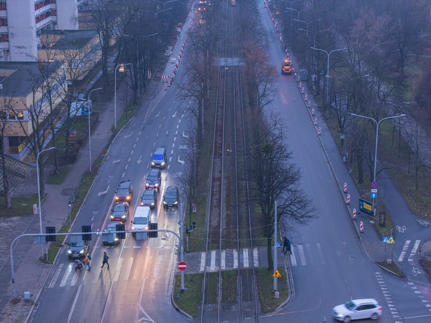 Widok z lotu ptaka na dwujezdniową ulicę, z torowiskiem tramwajowym po środku i budynki stojące przy niej. Wyremontowany fragment ul. Powstańców Śląskich.