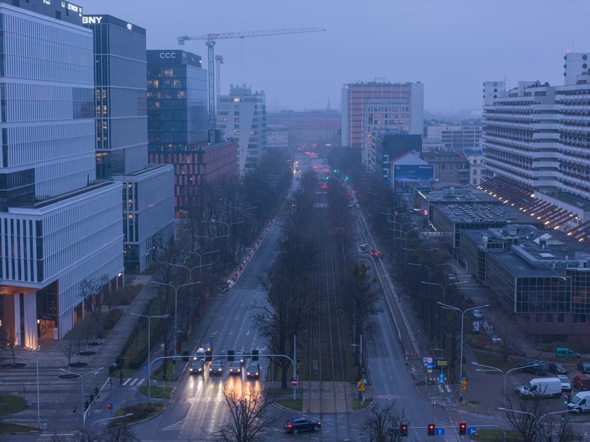Widok z lotu ptaka na dwujezdniową ulicę, z torowiskiem tramwajowym po środku i budynki stojące przy niej. Wyremontowany fragment ul. Powstańców Śląskich.