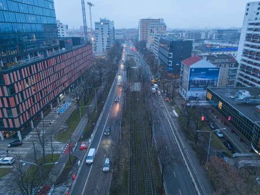 Widok z lotu ptaka na dwujezdniową ulicę, z torowiskiem tramwajowym po środku i budynki stojące przy niej. Wyremontowany fragment ul. Powstańców Śląskich.