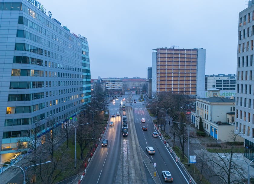 Widok z lotu ptaka na dwujezdniową ulicę, z torowiskiem tramwajowym po środku i budynki stojące przy niej. Wyremontowany fragment ul. Powstańców Śląskich.
