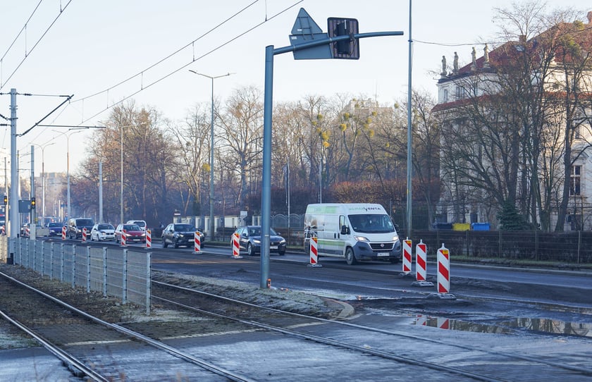 Jezdnia ze sfrezowanym asfaltem na jednym pasie i auta jadące po drugim - remontowany fragment ul. Powstańców Śląskich.