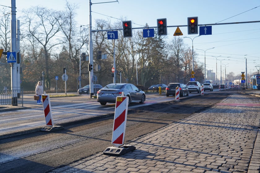 Jezdnia ze sfrezowanym asfaltem na jednym pasie i auta jadące po drugim - remontowany fragment ul. Powstańców Śląskich.