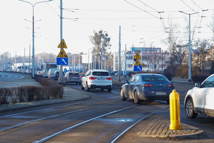 Jezdnia ze sfrezowanym asfaltem na jednym pasie i auta jadące po drugim - remontowany fragment ul. Powstańców Śląskich.
