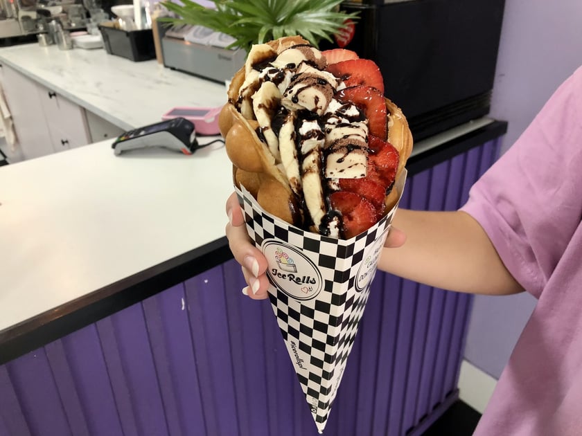 Ice rolls & Twojaczekoladka, znajduje się przy ul. Kuźniczej 10. Zamówisz tutaj bubble waffle w sześciu smakach: owocowy, oreo, nutella, kinder bueno (na zdjęciu), raffaello i masło orzechowe. Cena: 17 zł, a z dodatkową gałką lodów - 19 zł. Godziny otwarcia: od poniedziałku do soboty, w godz. od 10:00 do 22:00, w niedziele od 10:00 do 21:00.