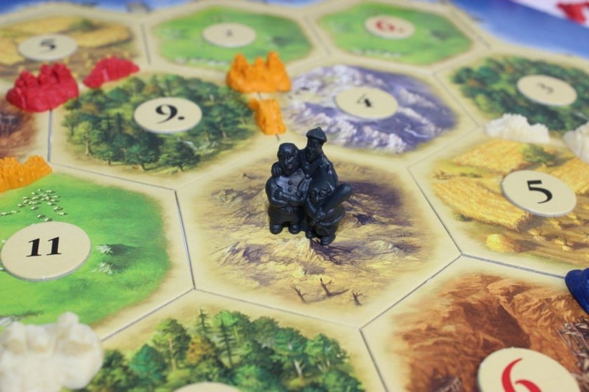 4. CATAN /// Gracze są osadnikami na niedawno odkrytej wyspie Catan. Każdy z nich przewodzi świeżo założonej kolonii i rozbudowuje ją stawiając na dostępnych obszarach nowe drogi i miasta. Każda kolonia zbiera dostępne dobra naturalne, które są niezbędne do rozbudowy osiedli. Gracz musi rozważnie stawiać nowe osiedla i drogi, aby zapewnić sobie dostateczny, ale zrównoważony dopływ zasobów, a jeśli ma ich nadmiar ? prowadzić handel z innymi graczami sprzedając im owce, drewno, cegły, zboże lub skały, a pozyskując od nich te zasoby, których mu brakuje. Pierwszy z graczy, który uzyska dziesięć punktów z wybudowanych przez siebie dróg, osiedli i specjalnych kart, wygrywa. /// wiek: 8+ /// liczba graczy: 3 ? 4