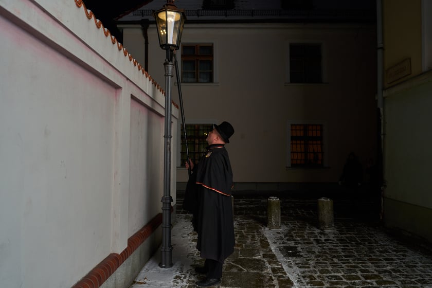 Na zdjęciu widać mężczyznę, który zapala latarnię na Ostrowie Tumskim we Wrocławiu