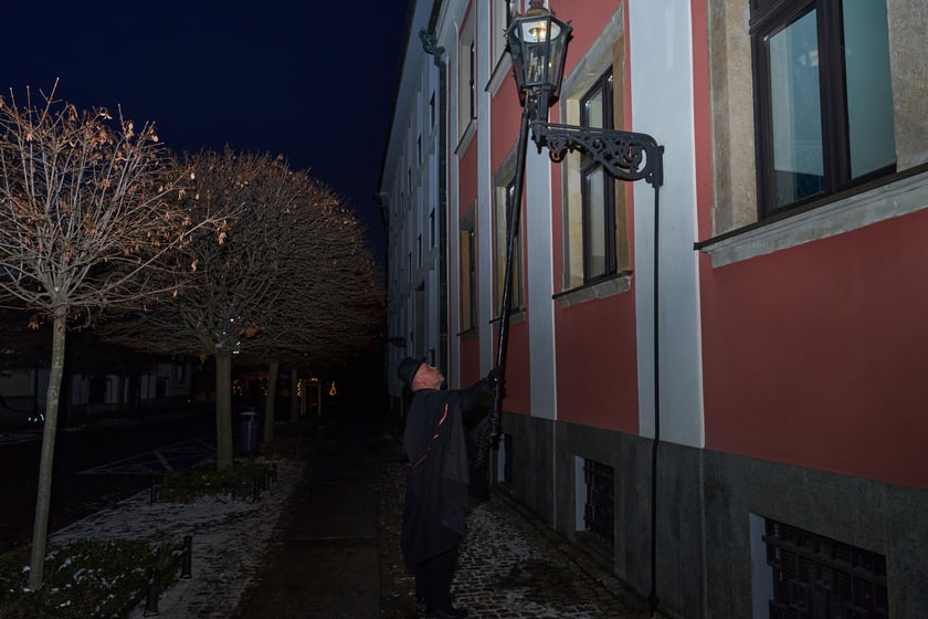 Na zdjęciu widać mężczyznę, który zapala latarnię na Ostrowie Tumskim we Wrocławiu