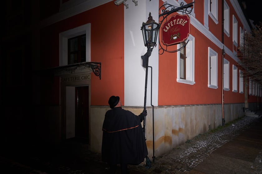 Na zdjęciu widać mężczyznę, który zapala latarnię na Ostrowie Tumskim we Wrocławiu