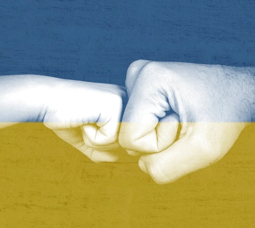 "Ukraina" była najszybciej zyskującym na popularności hasłem w Polsce wg zestawienia Google Trends 2022. Na zdjęciu dwie dłonie na tle flagi Ukrainy