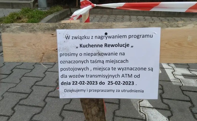 Na  zdjęciu widoczna jest kartka, na której jest napisane m.in. W związku z nagrywaniem programu ?Kuchenne rewolucje? prosimy o nieparkowanie na oznaczonych taśmą miejscach postojowych