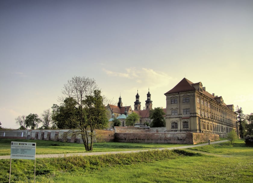 &bdquo;Lubiąż od początku swojej historii jest związany z cystersami, kt&oacute;rzy wybudowali klasztor. Ten rozległy kompleks, w kt&oacute;rym znajduje się ponad 300 pomieszczeń, do dziś jest świadectwem potęgi zamieszkujących tam niegdyś zakonnik&oacute;w.
Zesp&oacute;ł klasztorny w Lubiążu jest drugim pod względem wielkości tego typu obiektem w Europie. Długość fasady wynosi 223 m &ndash; jest to najdłuższa fasada barokowa w Europie. W krypcie pod gotycką bazyliką znajdują się nagrobki Piast&oacute;w śląskich. W kościele można zobaczyć freski Michała Wilmanna. Mistrz mieszkał w klasztorze przez wiele lat i malował na zam&oacute;wienie &oacute;wczesnego opata.&rdquo;
Zacytowano fragmenty opisu z "Atlasu Turystycznego. Dolny Śląsk&rdquo; &ndash; Wydawnictwo SBM &ndash; Warszawa 2021 &ndash; tekst: Monika Bronowicka.
Około 54 kilometry z Wrocławia.