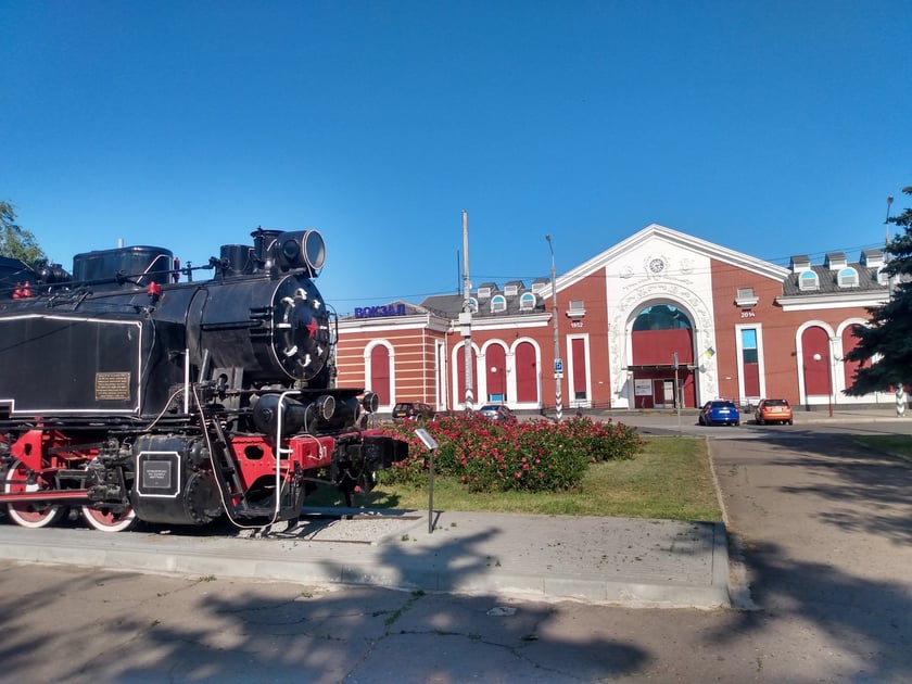 Zabytkowa lokomotywa i w tle dworzec kolejowy w Kramatorsku