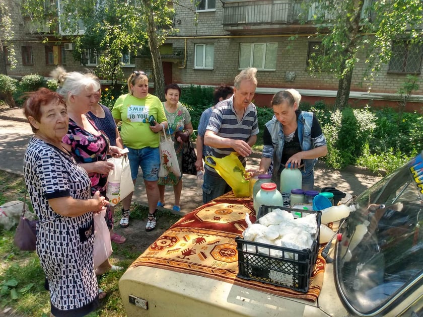 Mieszkańcy kupują mleko i śmietanę z maski Lady na podwórku przed blokiem.