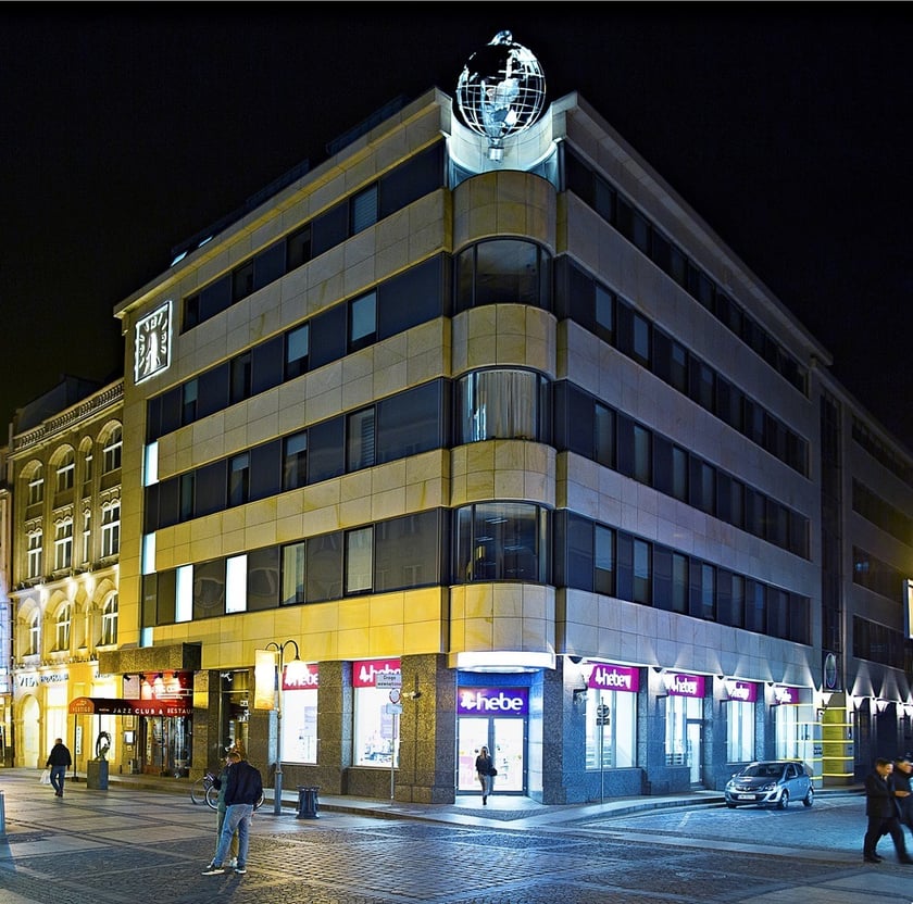 Aktualny wygląd biurowca Save The World, nocą widać podświetlone globus i zegar