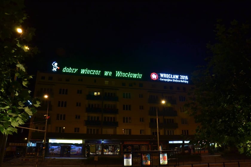 Wieczorny widok na budynek z neonem&nbsp;&bdquo;dobry wiecz&oacute;r we Wrocławiu&rdquo;, 2014-2016