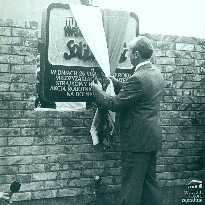 Obchody pierwszej rocznicy strajków sierpniowych. Jerzy Piórkowski odsłania tablicę upamiętniającą strajk w sierpniu 1980 r. umieszczoną na terenie zajezdni autobusowej nr VII przy ul. Grabiszyńskiej we Wrocławiu [na tablicy napis: „Tu rodziła się wrocławska Solidarność…”].