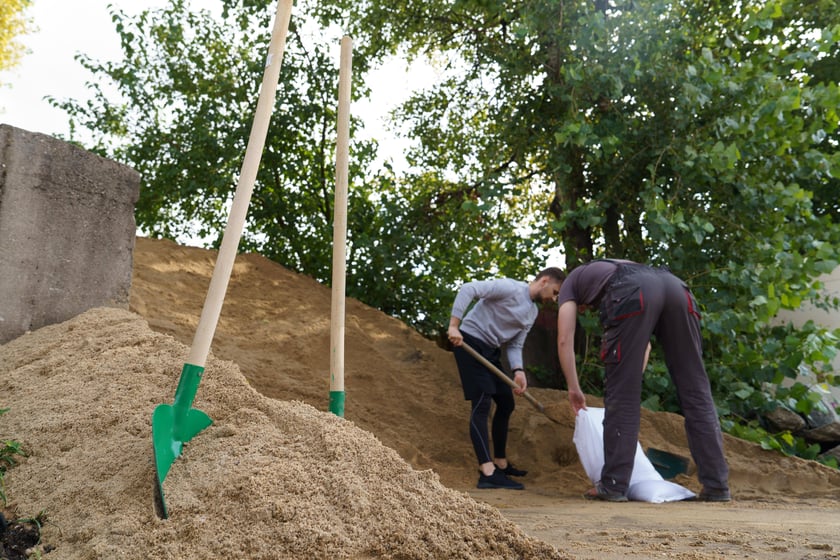 Mężczyźni sypiący piasek do worków