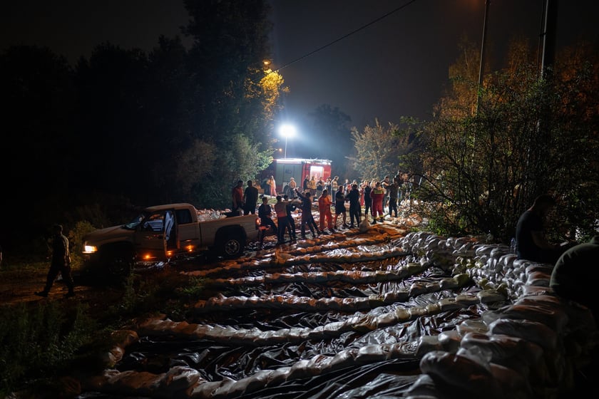 Kobiety i mężczyźni układają worki z piaskiem na Marszowicach w nocy z 17 na 18 września 2024 roku