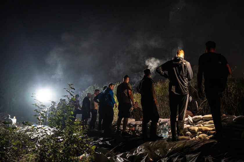 Kobiety i mężczyźni układają worki z piaskiem na Marszowicach w nocy z 17 na 18 września 2024 roku