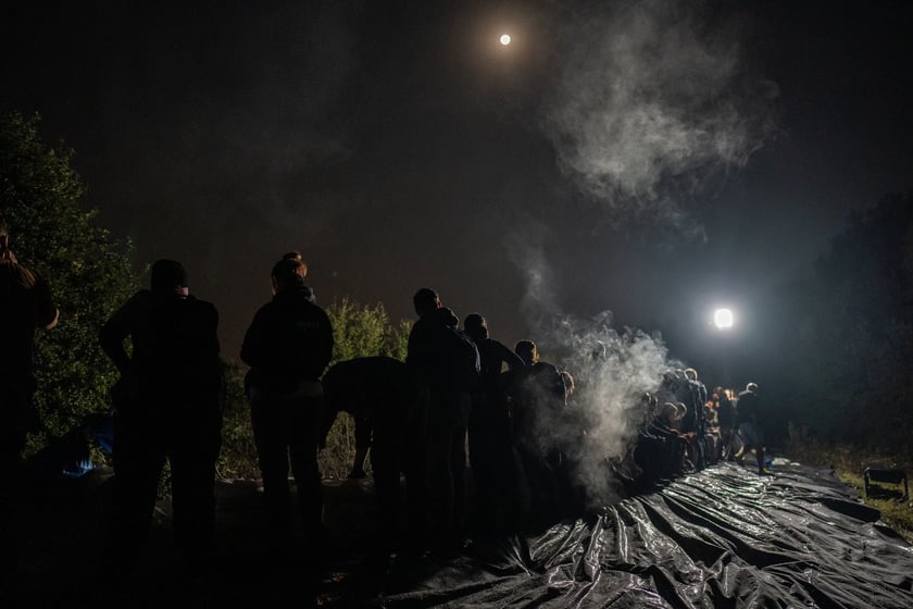 Kobiety i mężczyźni układają worki z piaskiem na Marszowicach w nocy z 17 na 18 września 2024 roku