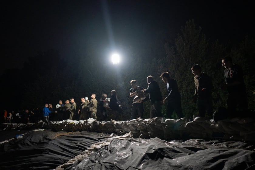 Kobiety i mężczyźni układają worki z piaskiem na Marszowicach w nocy z 17 na 18 września 2024 roku