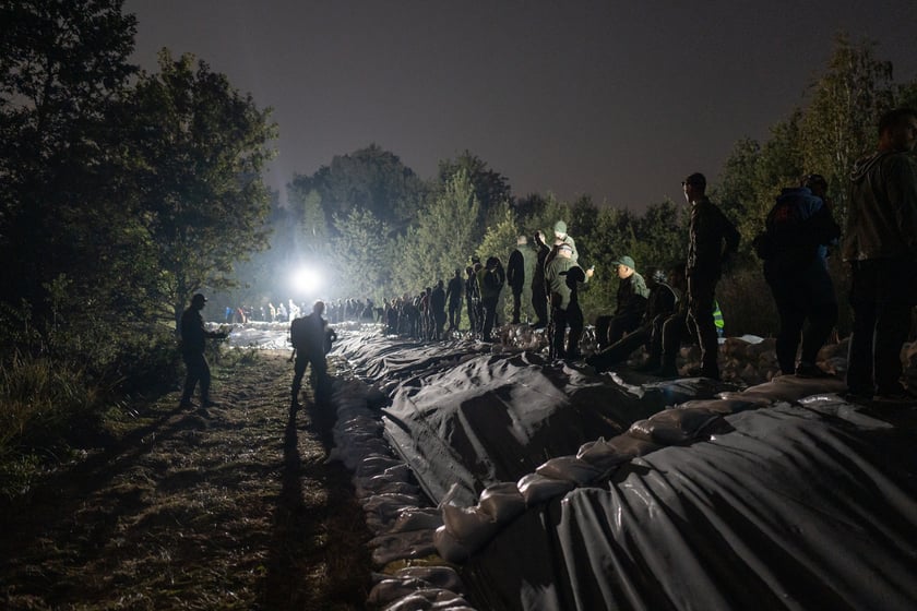Kobiety i mężczyźni układają worki z piaskiem na Marszowicach w nocy z 17 na 18 września 2024 roku