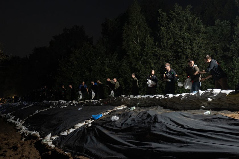 Kobiety i mężczyźni układają worki z piaskiem na Marszowicach w nocy z 17 na 18 września 2024 roku