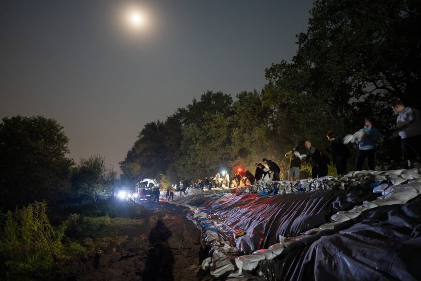 Kobiety i mężczyźni układają worki z piaskiem na Marszowicach w nocy z 17 na 18 września 2024 roku