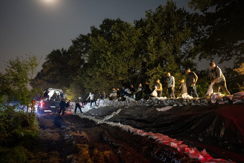 Kobiety i mężczyźni układają worki z piaskiem na Marszowicach w nocy z 17 na 18 września 2024 roku