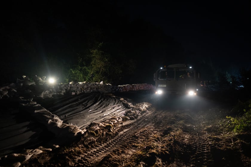 Kobiety i mężczyźni układają worki z piaskiem na Marszowicach w nocy z 17 na 18 września 2024 roku