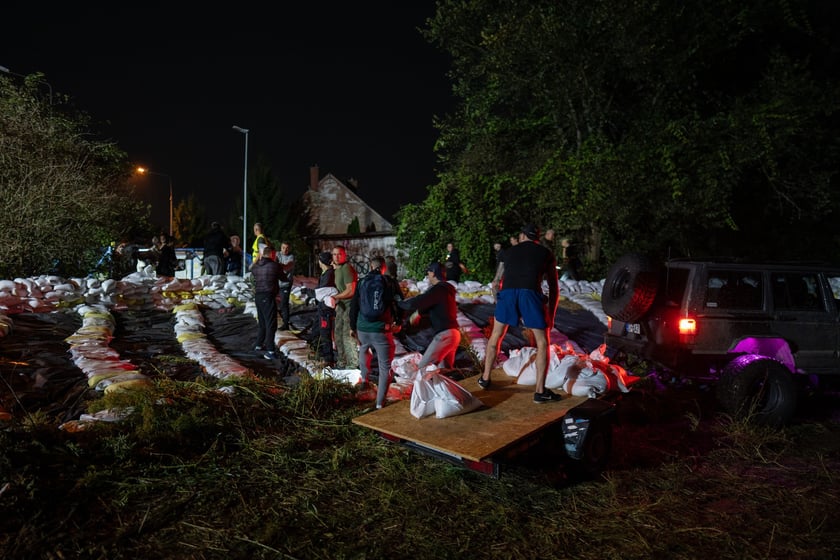 Kobiety i mężczyźni układają worki z piaskiem na Marszowicach w nocy z 17 na 18 września 2024 roku