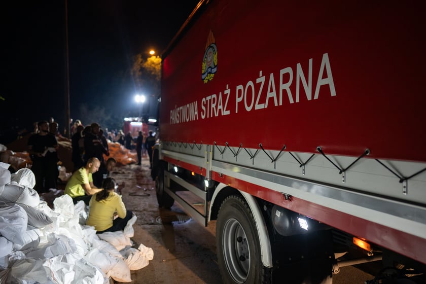 Kobiety i mężczyźni układają worki z piaskiem na Marszowicach w nocy z 17 na 18 września 2024 roku
