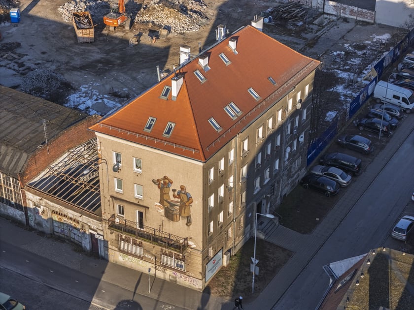 Mozaika na elewacji domu nr 11 przy ul. Ustronie pokazuje dw&oacute;ch kowali przy pracy