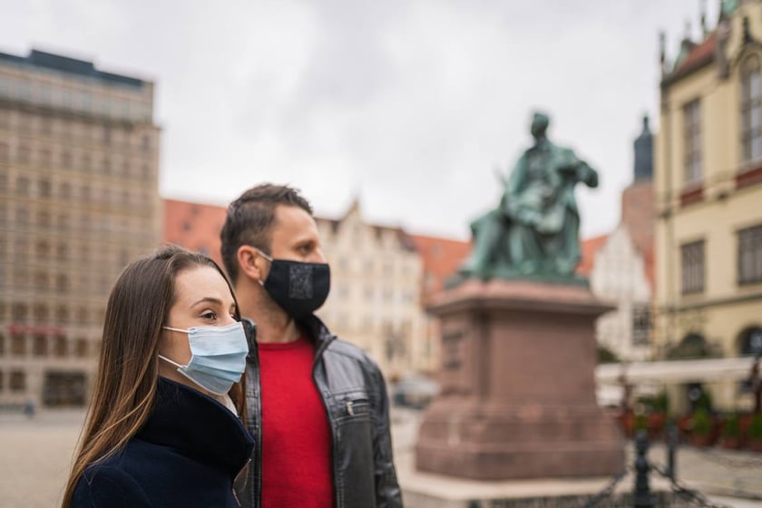 Kobieta i mężczyzna w maseczkach, w tle pomnik Fredy na rynku.