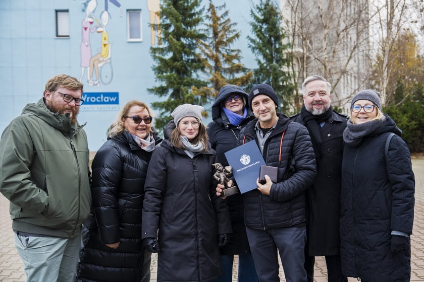 Andrzej Tylkowski, jeden z najbardziej rozpoznawalnych wrocławskich artyst&oacute;w z odznaką &bdquo;Zaslużony dla Wrocławia&rdquo; i krasnalem oraz zespołem Departamentu Marki Wrocławia i przedstawicielką firmy Wallart, kt&oacute;ra wykonała mural