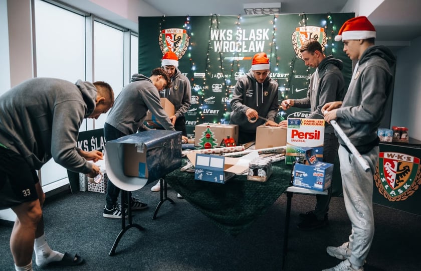 Powiększ obraz: Sześciu piłkarzy Śląska Wrocław pakuje świąteczne prezenty.