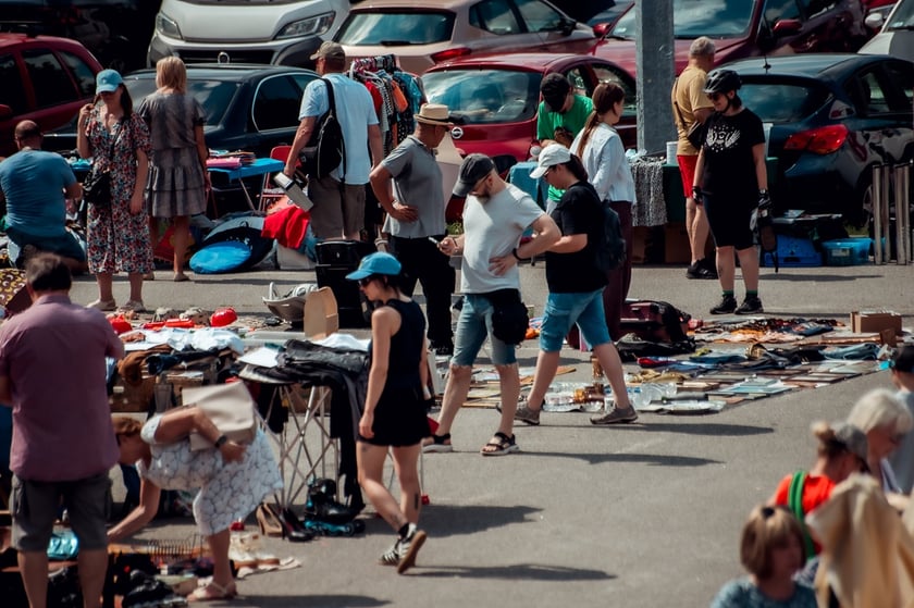 Plac przed CH Borek na którym widać ludzi i rozstawione stoiska z rzeczami wystawionymi na sprzedaż lub wymianę podczas Wrocławskiej Wymiany Garażowej
