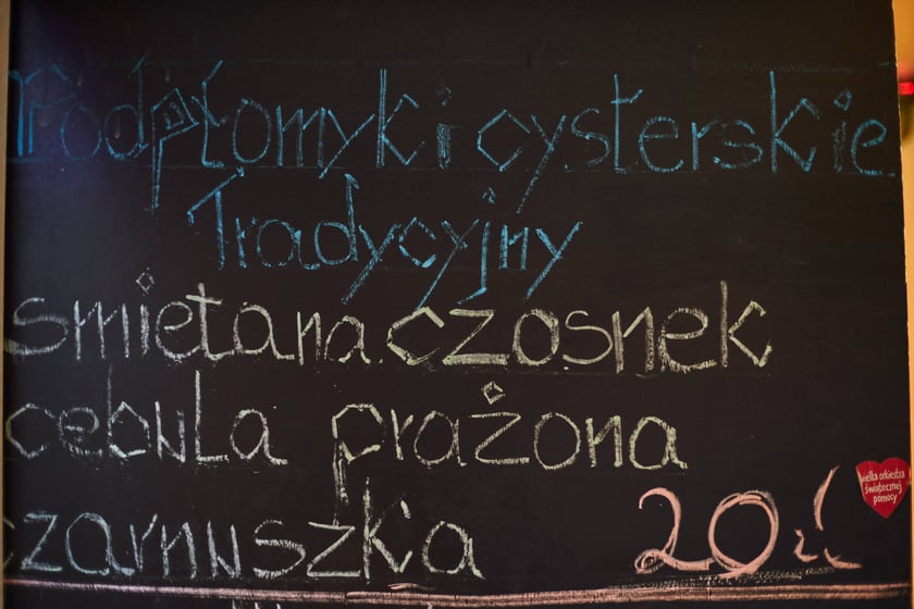 Zdjęcia z Jarmarku Bożonarodzeniowego we Wrocławiu. Na zdjęciu widać tablicę z nazwami potraw i cenami
