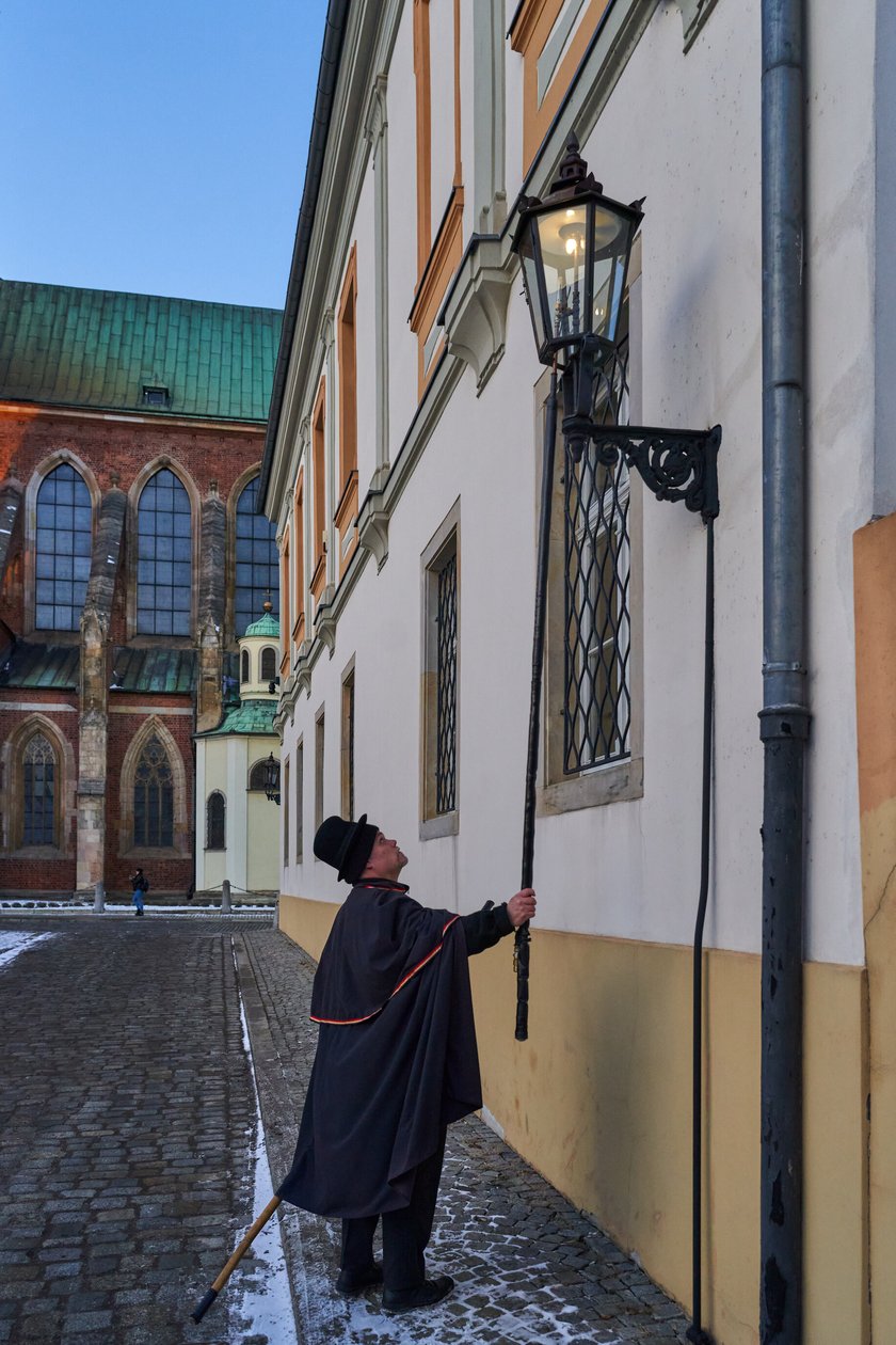 Na zdjęciu widać mężczyznę, który zapala latarnię na Ostrowie Tumskim we Wrocławiu